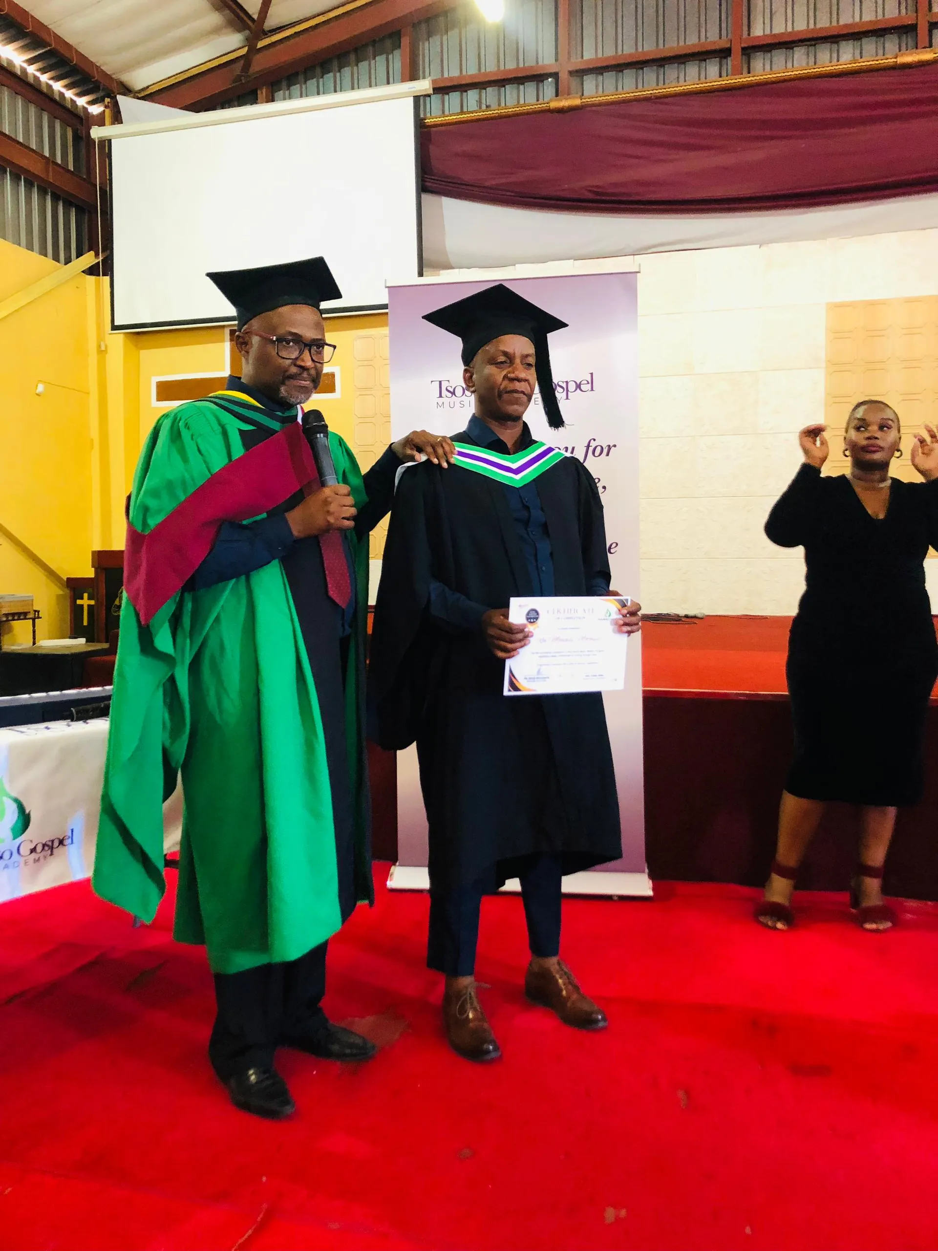 Jacob Khunwana presenting a graduation certificate to a student at the TGMA ceremony